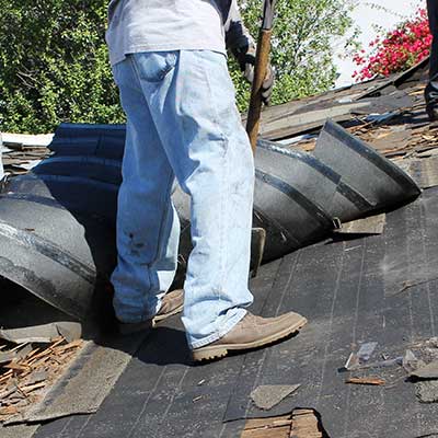 Roofer in the process of removing the old shingles of a residential roof